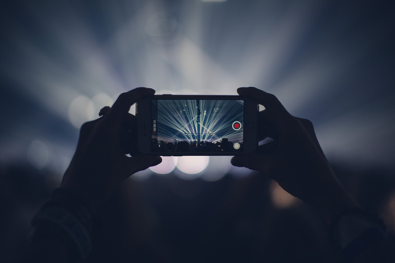 Pessoas gravando e interagindo com celular durante evento ao vivo