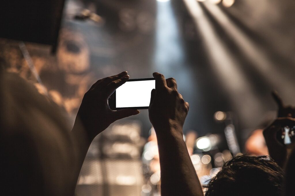 Pessoas filmando com celular em evento, representando marketing de influência esportivo