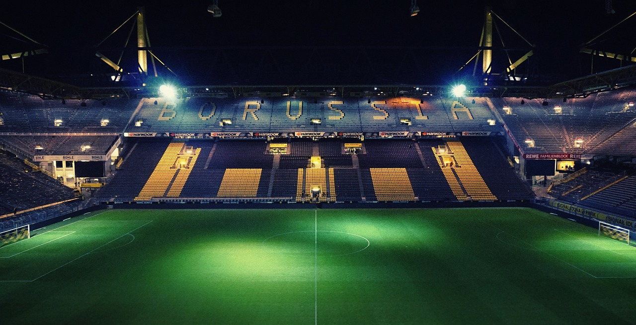 Arena de futebol iluminada durante partida à noite